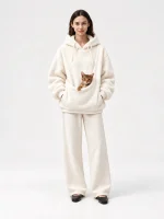 Model wearing a white unisex fleece pet carrier hoodie with a cat in the front pouch